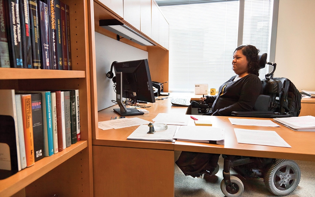 Liz Persaud at her desk demontrating an accessible desk