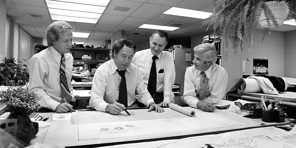 Picture of John Portman with other people over an architecturial desk