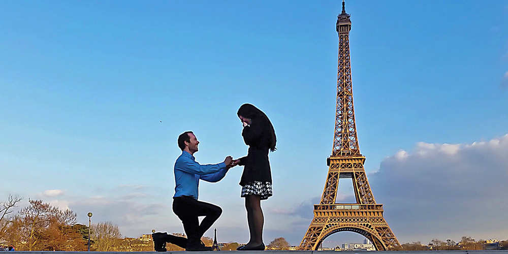 Brandon Cox proposing to his fiance with the Eifel Tower in the background